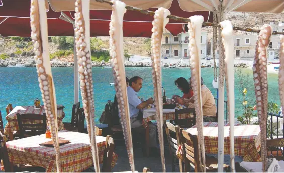  ?? RICK STEVES ?? As customers enjoy their meals, octopus tentacles hang to dry on a waterfront terrace in the sunny Peloponnes­e peninsula of Greece, an appealing area worth exploring.