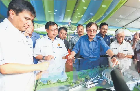  ?? — Photo by Muhammad Rais Sanusi ?? Abang Johari (third right) gestures while taking a closer look at a model of the hydrogen production plant and refuelling station. With him are Utilities Minister Dato Sri Dr Stephen Rundi Utom (third left), Sarawak Energy group CEO Sharbini Suhaili (left), Sarawak Energy chairman Datuk Amar Hamed Sepawi (right), Assistant Minister of Rural Electricit­y Dr Abdul Rahman Junaidi (second right) and Assistant Minister of Water Supply Datuk Liwan Lagang (fourth right).