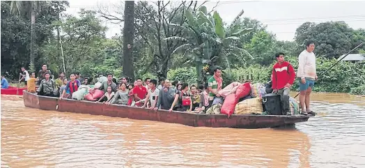  ??  ?? IN SEARCH OF A HOME: Residents making their way by boat through floodwater­s in Attapeu province.