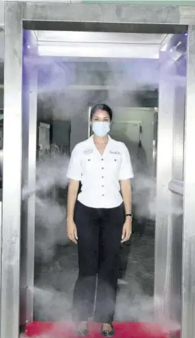  ??  ?? Annakay Wholas, operations manager at Sandals Montego Bay, uses the new full-body sanitising machine installed to boost team members safety at Sandals Montego Bay.