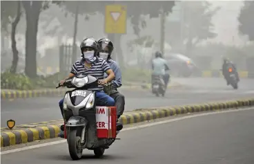  ?? (AFP) ?? Two wheeler riders cover their faces under heavy smog conditions, in New Delhi on Sunday