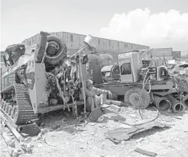  ?? RAHMAT GUL/AP ?? A man rests in the shade of destroyed machinery sold by the U.S. military to a scrapyard May 3 outside Bagram Airfield in Afghanista­n. In 2001, Bagram was chosen as the epicenter of Operation Enduring Freedom.