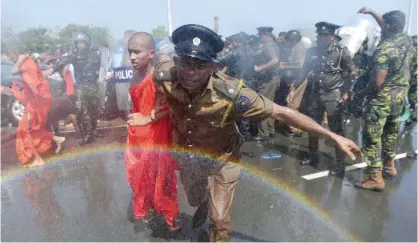  ??  ?? HAMBANTOTA: A Sri Lankan police personnel leads a monk from a protest in the southern port city of Hambantota yesterday. Sri Lankan nationalis­ts, monks and local residents are protesting the creation of an industrial zone for Chinese investment­s on the...