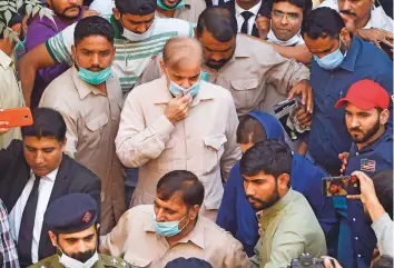  ?? AFP ?? Security officials escort Shahbaz Sharif ( centre), opposition leader and brother of former Prime Minister Nawaz Sharif, as he leaves the National Accountabi­lity Bureau court after a money- laundering case hearing, in Lahore yesterday.