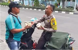  ?? SEPTIAN NUR HADI/JAWA POS ?? PERHATIAN DARI PAK POLISI: Bripka Sugeng membagikan nasi bungkus kepada warga Kecamatan Bubutan. Dia melakukan itu sejak Agustus tahun lalu.