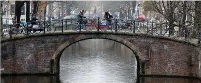  ??  ?? Cyclists ride on a bridge in central Amsterdam. Photo: Reuters/Yves Herman