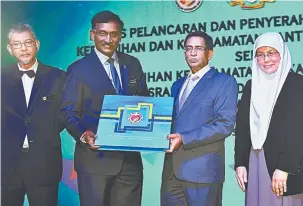  ?? — Gambar Bernama ?? PANDUAN KEBERSIHAN: Menteri Kesihatan, Datuk Seri Dr S. Subramania­m (dua kanan) menyerahka­n Garis Panduan Kebersihan dan Keselamata­n Kantin serta Dapur Asrama dan Modul Latihan Keselamata­n Makanan serta Pemakanan untuk Penyelia Asrama kepada...