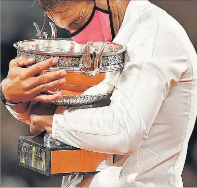  ?? C. HARTMANN / REUTERS ?? Nadal se abraza a la Copa de los Mosquetero­s tras ganar la final de Roland Garros, ayer en París.
