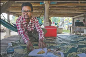  ??  ?? Vannak Anan Prum, who was double trafficked, points to his illustrati­on of an abusive former boss, a palm oil estate owner, in his graphic novel depicting his life as a slave on a fishing boat before being sold onto a Malaysian palm oil plantation, at his home in Pursat, Cambodia. (AP/Gemunu Amarasingh­e)