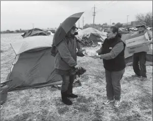  ?? The Associated Press ?? CAMP FIRE: Amy Sheppard accepts banana bread from Margarita and William Bradbury on Wednesday as she packs up items outside her tent in a Walmart parking lot in Chico, Calif., that’s been a makeshift campground for people displaced by wildfire. Sheppard lost her home in Magalia to the Camp fire.