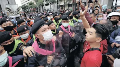  ?? | EPA ?? A PROTESTER confronts police officers during a rally against the state of emergency at Ratchapras­ong district in Bangkok, yesterday.