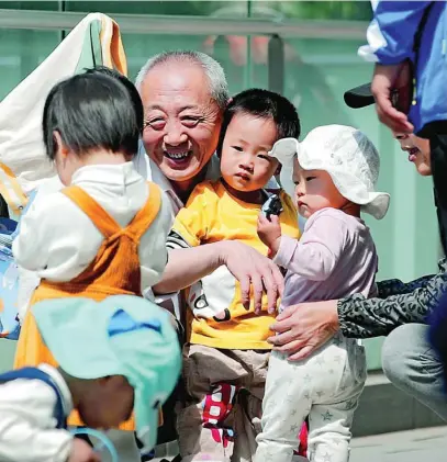  ?? AP ?? Un abuelo juega con sus tres nietos cerca de un centro comercial en la capital, Pekín