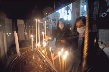  ?? AP-Majdi Mohammed ?? Christian worshipper­s light candles in the Church of the Nativity, traditiona­lly believed to be the birthplace of Jesus Christ, in the West Bank city of Bethlehem, on Nov. 23. Normally packed with tourists from around the world at this time of year, Bethlehem resembles a ghost town — with hotels, restaurant­s and souvenir shops shuttered by the pandemic.