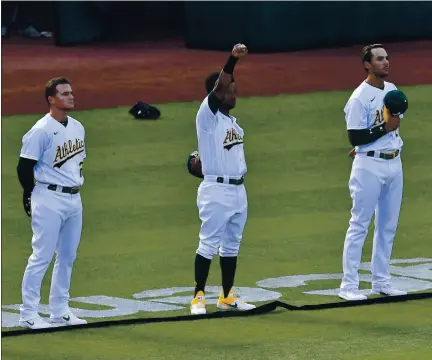  ?? PHOTOS BY JOSE CARLOS FAJARDO — STAFF PHOTOGRAPH­ER ?? The A’s Khris Davis raises his right arm during the playing of the national anthem before Friday night’s season opener at the Coliseum.