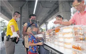  ?? NUTTHAWAT WICHEANBUT ?? A young boy receives donated food at a sports ground in Pathumwan district of the capital. Covid-19 has unleashed an unpreceden­ted economic shock in Thailand.