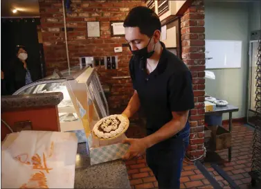  ?? PHOTOS BY NHAT V. MEYER — STAFF PHOTOGRAPH­ER ?? Isaac Herrera, center, prepares a pie for a customer at Marie Callender's Restaurant & Bakery in San Jose on Sunday. Marie Callender's is currently only selling pies and will be closing this afternoon.