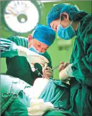  ?? TONG LIANG / FOR CHINA DAILY ?? Doctors in Wuhan perform surgery on Zhao Xuecheng, who was badly burned as an infant.