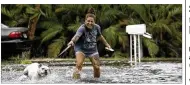  ?? ANDREW WEST / THE NEWS-PRESS ?? Darcelle Jacobs and her dog Skittles check out the flooding on their street in Fort Myers Beach, Fla., Monday. Tropical Storm Emily weakened to a tropical depression as it moved across Florida.