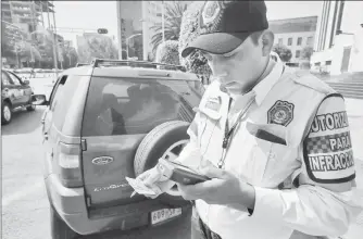  ??  ?? Un oficial de tránsito de la Secretaría de Seguridad Pública capitalina impone una multa a un conductor que transgredi­ó la norma vial ■ Foto Carlos Ramos Mamahua