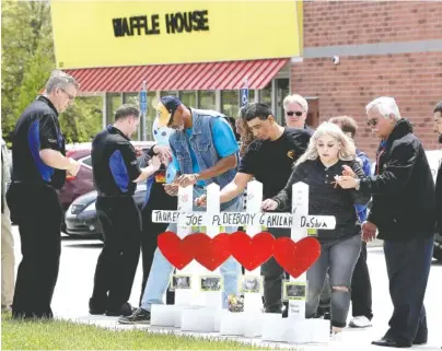  ?? AP PHOTO BY MARK HUMPHREY ?? Family members of people killed at a Waffle House restaurant write messages on wooden crosses set up as a memorial Wednesday in Antioch, Tenn. Four people were killed when a gunman opened fire at the restaurant Sunday. Members of the Waffle House...