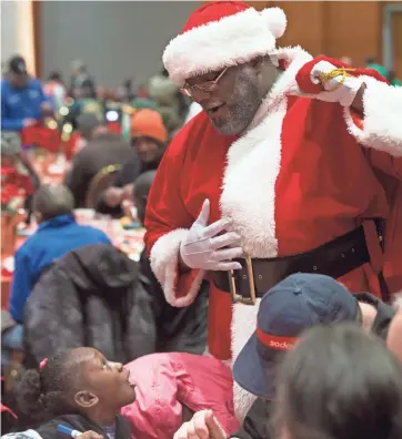  ?? MARK HOFFMAN / MILWAUKEE JOURNAL SENTINEL ?? A girl is charmed by the appearance of Santa (Robert Boyd) at the 27th Annual Salvation Army Christmas Family Feast on Sunday at the Wisconsin Center. More than 8,000 meals were served there and at shelters across the city. “The Christmas Family Feast...