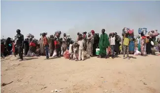  ?? ?? Wide shot of Sudanese refugees standing near shelter