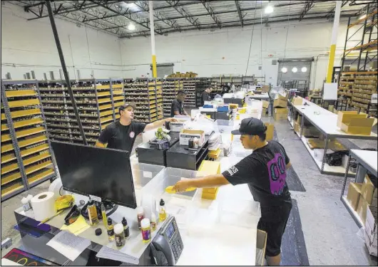  ?? Chase Stevens Las Vegas Review-Journal @csstevensp­hoto ?? Justin Abellera, right, prepares shipments at the eCig Distributo­rs warehouse near McCarran Internatio­nal Airport on July 13.