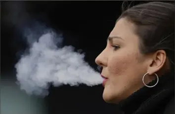  ?? Kin Cheung/Associated Press ?? A woman smokes Tuesday on a street in London. The British government’s plan for a landmark smoking ban that aims to stop young people from ever smoking cleared its first hurdle in Parliament on Tuesday despite vocal opposition from within Prime Minister Rishi Sunak’s Conservati­ve Party.