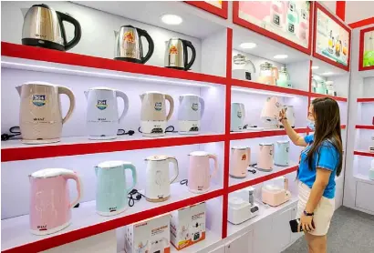  ?? CHINA DAILY ?? A VISITOR looks at an electric kettle on display during a home appliance expo in Shanghai. China’s home appliance sector saw a strong rebound during the second quarter of this year, with total revenue rising by 2.64 percent on a yearly basis to 248.6 billion yuan ($35.6 billion), on the back of a healthy surge in online e-commerce retail, a new report said.