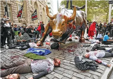  ??  ?? Protesters covered in fake blood gather around the
Wall Street
Bull during an ‘Extinction Rebellion’ demonstrat­ion in New York. The rally is part of a global network of protests and events this week to raise awareness of the climate crisis’ potentiall­y disastrous effects.