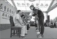  ?? Suona, PHOTOS BY ZHOU YI / CHINA NEWS SERVICE ?? Above: Foreigners bow to inheritors of intangible cultural heritage to become their apprentice­s during an event in Chongqing. Below: An inheritor teaches his foreign apprentice to play a musical instrument, at the event.