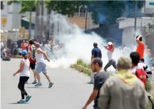  ?? AFP ?? Opposition supporters run past a tear-gas cloud during clashes in Caracas, Venezuela. —