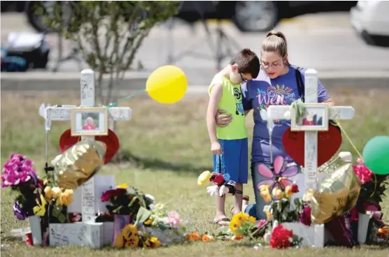  ?? SCOTT OLSON/ GETTY IMAGES ?? Mourners visit a makeshift memorial in front of Santa Fe High School on Tuesday to honor the victims of last Friday’s Texas school shooting that left 10 people dead.
