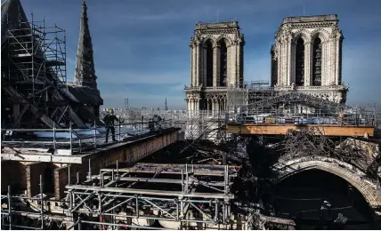  ?? (Martin Bureau/AFP/Getty Images) ?? WORKERS ON the roof of Notre-Dame work to remove the burnt scaffoldin­g that hampered the safety of the cathedral damaged by the 2019 fire, a year later in Paris.