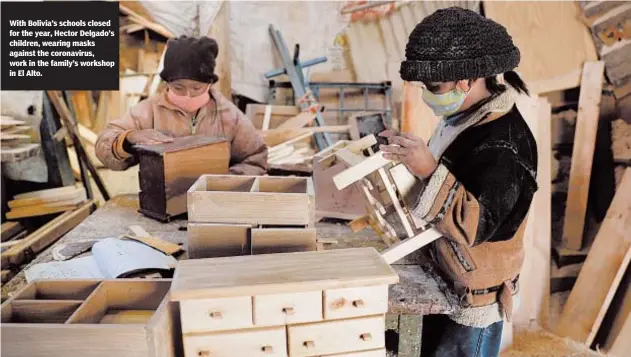  ??  ?? With Bolivia’s schools closed for the year, Hector Delgado’s children, wearing masks against the coronaviru­s, work in the family’s workshop in El Alto.