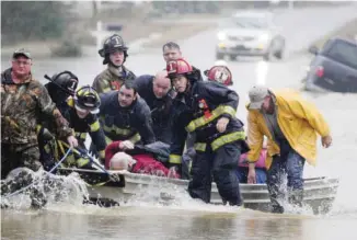  ??  ?? MOULTON, Alabama: Emergency officials transport a resident by boat because water over Byler Road prevented them from reaching him on Friday, before loading him into an ambulance. — AP