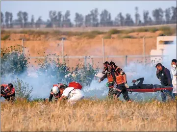  ??  ?? Palestinia­n paramedics carry an injured protester during a demonstrat­ion near the border between Israel and Khan Yunis in the southern Gaza Strip. —AFP photo