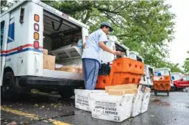  ?? AP PHOTO/J. SCOTT APPLEWHITE ?? Letter carriers load mail trucks for deliveries at a U.S. Postal Service facility in McLean, Va., on Friday.