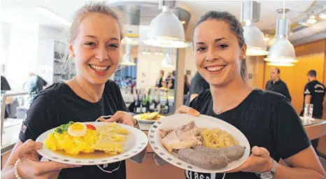  ?? FOTO: SCHOLZ ?? Leonie Bausch (links) und Aline Kölle servieren die Köstlichke­iten beim Schlachtfe­st in der Gemeindeha­lle Merklingen.