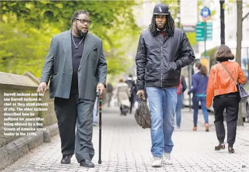  ?? AP ?? Darrell Jackson and his son Darrell Jackson Jr. chat as they stroll streets of city. The elder Jackson described how he suffered for years after being abused by a Boy Scouts of America scout leader in the 1970s.