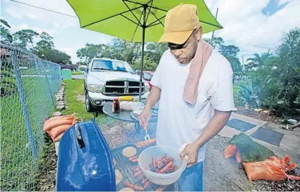  ?? RED HUBER/STAFF PHOTOGRAPH­ER ?? Ray J. Stubbs grills burgers, hot dogs and sausages for family and friends as OUC workers begin the process of restoring power to his neighborho­od.