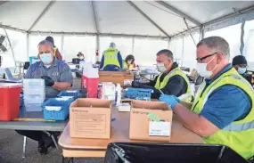  ?? ARIEL COBBERT/THE COMMERCIAL APPEAL ?? Colliervil­le firemen prepare the COVID-19 vaccine for distributi­on at the Germantown Baptist drive-thru vaccinatio­n site on March 10. About 1,000 doses per day are distribute­d at the site.