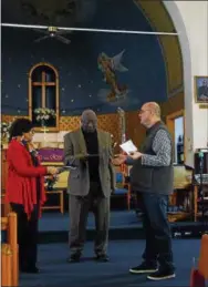  ??  ?? Our Lady of the Rosary member Peter DiMaio, right, presents gifts to Holy Tabernacle member Charlotte Parr, left and Rev. Ronald Savage Thursday morning.