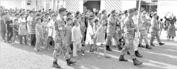  ??  ?? Children being escorted by ATM personnels waiting for water cannon spray in front of Al-Kauthar Mosque yesterday. - Bernama photo