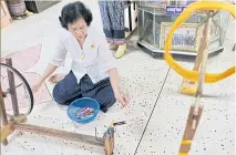  ??  ?? A woman spins silk yarn on a spinning wheel.