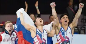  ?? — AFP ?? Jubilation: Russia’s Artur Dalaloyan (right) and David Belyavskiy (centre) react after they won the men‘s team final at the World Gymnastics Championsh­ips at the Hanns-Martin-Schleyer-Halle in Stuttgart on Wednesday. Russia won the gold medal ahead of China (silver) and Japan (bronze).
