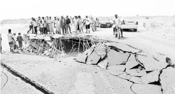  ??  ?? People look at the damage on a bridge hit by a Saudi-led air strike near the northweste­rn city of Harad,Yemen. — Reuters photo