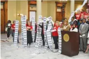  ?? ROSS WILLIAMS/GEORGIA RECORDER ?? Gun safety advocates unroll lists of shooting victims Feb. 17 at the Georgia Capitol in Atlanta.