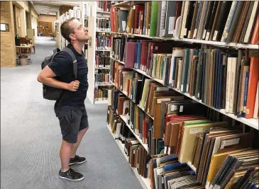  ?? RALPH K.M. HAURWITZ / AMERICAN-STATESMAN ?? Jeremy Ney, a postgradua­te musicology researcher from King’s College London, looks at some of the materials, including musical scores, on the fifth floor of UT’s Fine Arts Library.