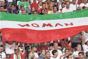  ?? FADEL SENNA,/AFP VIA GETTY IMAGES ?? Iran supporters wave their national flag bearing the word “woman” as they cheer during the World Cup match against England.